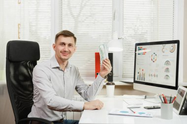 Yakışıklı gülümseyen iş adamı ile masada oturan gömlek 