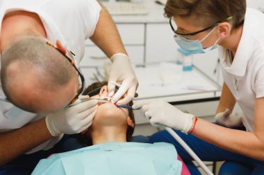 Hazırlama ve seramik diş taç yükleme işlemi. Diş Kliniği hafif ofis modern araçlar ekipman ile kadın hastanın tedavisi için yardımcı olur erkek profesyonel diş hekimi ve kadın Yardımcısı.