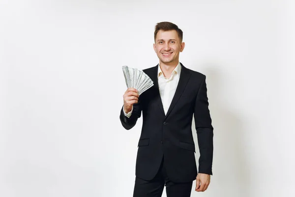 Giovane uomo d'affari ricco di successo in abito nero in possesso mazzetta di dollari in contanti isolati su sfondo bianco per la pubblicità. Concetto di denaro, realizzazione, carriera e ricchezza in 25-30 anni . — Foto Stock