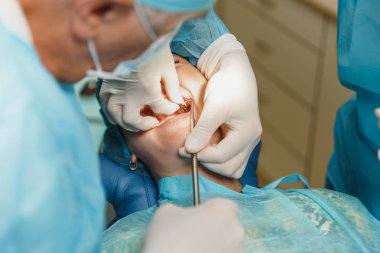 Erkek profesyonel diş hekimi cerrah işlemi gerçekleştirme süreci yakından kadın hastanın dental implant diş Kliniği hafif ofis modern araçlar ekipman ile yükleyin. Kan ve acı yüzünde.