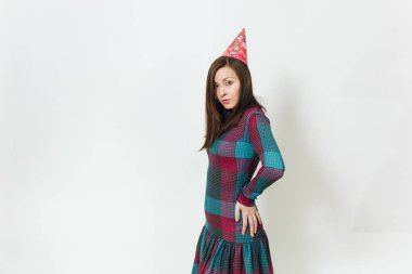 Güzel beyaz eğlenceli kutluyor ve zevk mutlu kadın ekose elbise ve doğum günü parti şapkası utangaç çekici gülümseme ve kahverengi saç, tatil için reklam izole beyaz arka plan üzerinde.