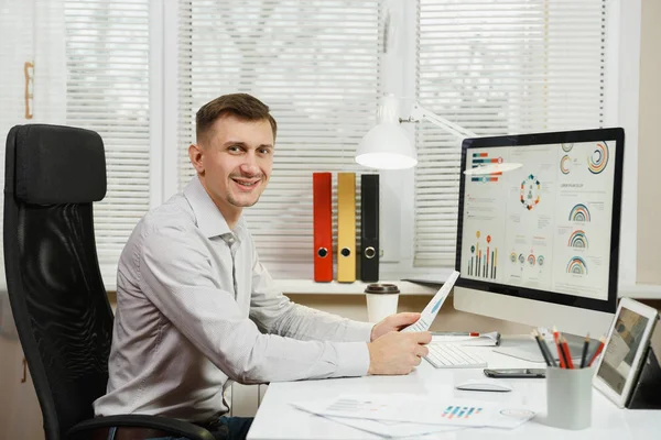 Çalışma masasında oturan gömlek gülümseyen yakışıklı iş adamı