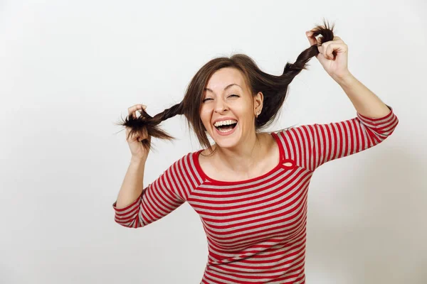 Linda jovem europeia feliz mulher de cabelos castanhos com pele limpa e saudável e sorriso encantador, vestida com roupas vermelhas e cinzentas casuais, enganando e rindo em um fundo branco. Conceito de emoções . — Fotografia de Stock