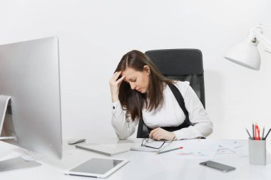 Güzel çapraşık yorgun ve belgeleri ve beyaz arka plan üzerinde ışık ofiste monitör ile çağdaş bilgisayarda çalışan brown-iş kadın takım elbise ve masa başında oturan gözlük stres