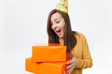 Güzel beyaz eğlence genç hevesli kadın doğum günü parti şapkası turuncu hediye kutuları ile mevcut, kutluyor tatil için reklam izole beyaz arka planda tutan sarı giysili.