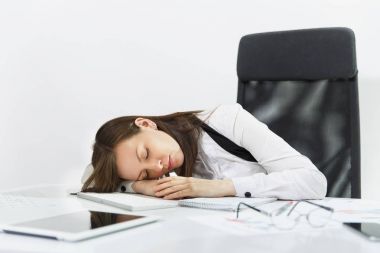 Güzel çapraşık yorgun ve kahverengi-iş kadın takım elbise ve beyaz arka plan üzerinde ışık Office belgeleri ile çağdaş bilgisayarda çalıştıktan sonra masada uyuyan gözlük stres