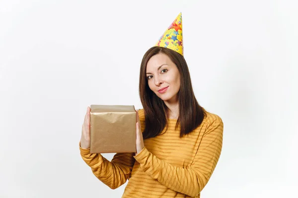 Jovem mulher feliz caucasiana alegre em roupas amarelas, chapéu de festa de aniversário segurando caixa de presente de ouro com presente, celebrando férias em fundo branco isolado para propaganda. Com lugar para texto — Fotografia de Stock