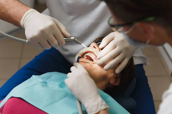 Hautnah Prozess der Vorbereitung und Installation der Zahnkeramikkrone. männliche professionelle Zahnarzt hilft, die Zähne der Patientin in der Klinik light Büro mit modernen Werkzeugen Ausrüstung zu behandeln. Mund auf. — Stockfoto