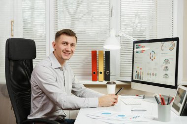 Yakışıklı gülümseyen iş adamı ile masada oturan gömlek 