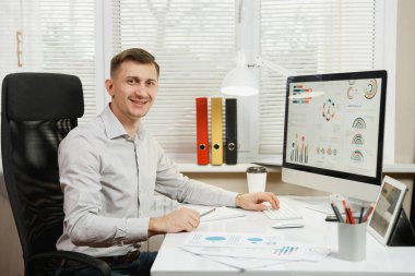 Çalışma masasında oturan gömlek gülümseyen yakışıklı iş adamı