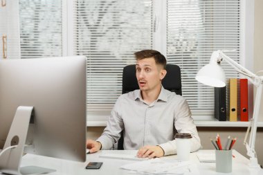 Çapraşık şok ve bilgisayarda çalışan modern monitör, klasörler, lamba, belge penceresi arka plan üzerinde ışık Office ile iş adamı masa başında oturan gömlek stres. Yöneticisi veya alt.