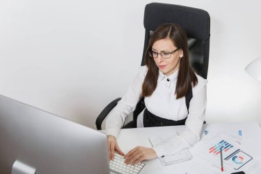 Beyaz arka plan üzerinde klavye üzerinde eller hafif Office belgeleri ile çağdaş monitör bilgisayarda çalışan güzel gülümseyen brown-iş kadın takım elbise ve masa başında oturan gözlük