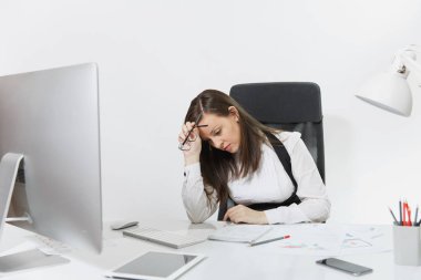 Güzel çapraşık yorgun ve belgeleri ve beyaz arka plan üzerinde ışık ofiste monitör ile çağdaş bilgisayarda çalışan brown-iş kadın takım elbise ve masa başında oturan gözlük stres