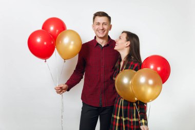 Güzel genç mutlu gülümseyen çift aşık. Kadın ve adam izole beyaz arka plan üzerinde doğum günü kutlama kırmızı, sarı balonları, ekose kareli giysiler içinde. Tatil, parti konsept.
