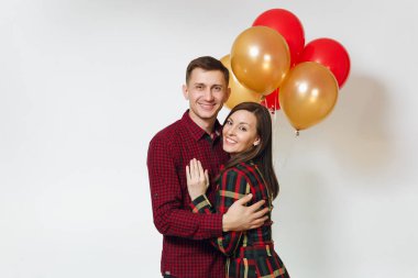 Güzel genç mutlu gülümseyen çift aşık. Kadın ve adam izole beyaz arka plan üzerinde doğum günü kutlama kırmızı, sarı balonları, ekose kareli giysiler içinde. Tatil, parti konsept.