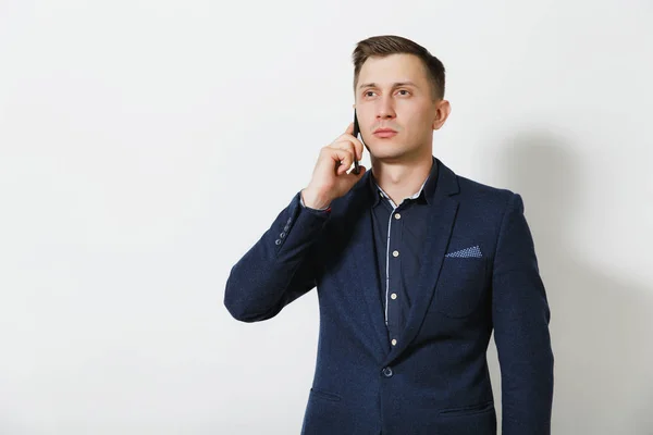 Красивый кавказский молодой бизнесмен в синем классическом костюме, разговаривает по мобильному телефону, ведет приятный разговор, изолирован на белом фоне. Менеджер, работник. Копирование места для рекламы — стоковое фото