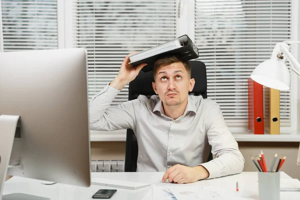 Shocked perplexed and stress business man in shirt sitting at the desk, working at computer with modern monitor, folders, lamp, documents in light office on window background. Manager or worker. — Stock Photo, Image