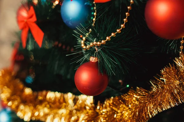 Yılbaşı ağacı süsleri cam ile yakından kırmızı, renkli mavi topları, altın gelin teli, kırmızı yay, boncuk glitter ve sıcak aydınlatma detay altın dizeleri. Yeni yıl ve tatil 2018 kavramı. — Stok fotoğraf