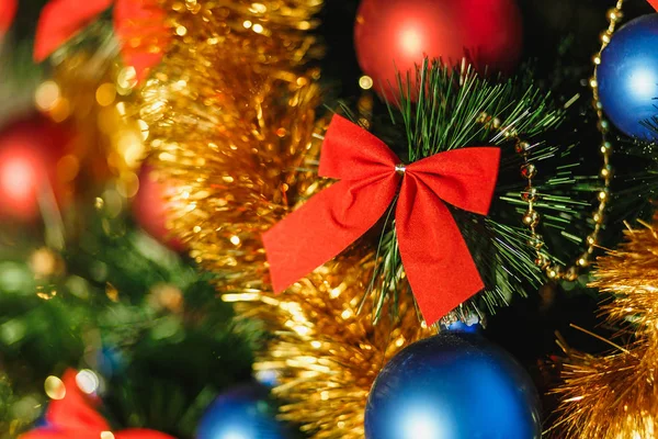 Nahaufnahme Christbaumschmuck aus Glas mit farbigen roten, blauen Kugeln, goldenem Lametta, roten Schleifen, goldenen Perlenketten mit Glitzern und warmen Beleuchtungsdetails. Neues Jahres- und Urlaubskonzept 2018. — Stockfoto