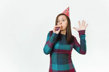 Güzel beyaz eğlence genç mutlu kadın ekose elbise ve doğum günü parti şapkası utangaç bir gülümseme büyüleyici, boru oynatma, kutlama ve beyaz arka plan üzerinde tatil keyfini ile reklam için izole.