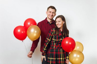 Güzel genç mutlu gülümseyen çift aşık. Kadın ve adam izole beyaz arka plan üzerinde doğum günü kutlama kırmızı, sarı balonları, ekose kareli giysiler içinde. Tatil, parti konsept.