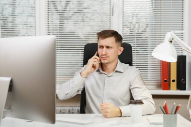 Cep telefonu üzerinde konuşurken ciddi iş adamı masa başında oturan gömlek sorunları, bilgisayar başında modern monitör, belge penceresi arka plan üzerinde ışık ofiste çalışan çözümleniyor. Yöneticisi veya alt