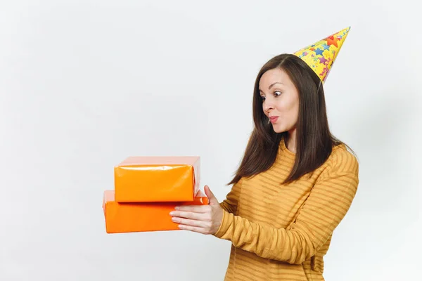 Piękna zabawna kaukaski młody szczęśliwą kobietą w żółty ubrania, urodziny party hat trzymając pomarańczowe pudełeczka z teraźniejszości, obchodzi i cieszyć się wakacje na białym tle odizolowane na ogłoszenie. — Zdjęcie stockowe