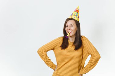 Güzel beyaz eğlence genç mutlu kadın kutluyor ve reklam için izole beyaz arka plan üzerinde tatil keyfini boru, oynayan sarı giysiler ve doğum günü parti şapkası kahverengi uzun saçlı.