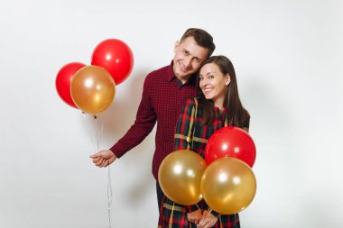 Güzel genç mutlu gülümseyen çift aşık. Kadın ve adam izole beyaz arka plan üzerinde doğum günü kutlama kırmızı, sarı balonları, ekose kareli giysiler içinde. Tatil, parti konsept.