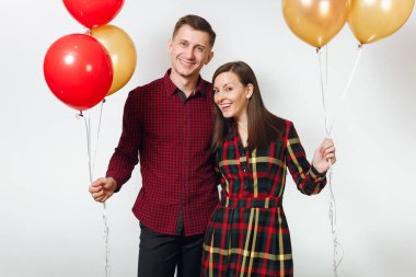 Güzel genç mutlu gülümseyen çift aşık. Kadın ve adam izole beyaz arka plan üzerinde doğum günü kutlama kırmızı, sarı balonları, ekose kareli giysiler içinde. Tatil, parti konsept.
