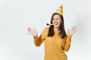 Güzel beyaz eğlenceli boru oynarken, tatil kutluyor, eller için reklam izole beyaz arka plan üzerinde yayılan genç mutlu kadın sarı giysiler ve doğum günü parti şapkası kahverengi uzun saçlı.