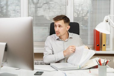 Bilgisayarda çalışan modern monitör, kırmızı klasör, belge penceresi arka plan üzerinde ışık Office ile yakışıklı ciddi ve dalmış iş adamı masa başında oturan gömlek. Yöneticisi veya alt.