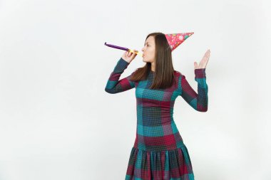 Güzel beyaz eğlence genç mutlu kadın ekose elbise ve doğum günü parti şapkası utangaç bir gülümseme büyüleyici, boru oynatma, kutlama ve beyaz arka plan üzerinde tatil keyfini ile reklam için izole.