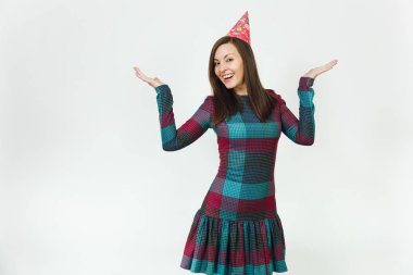 Kutluyor ve eller için reklam yaymak izole, beyaz arka plan üzerinde tatil keyfini güzel genç mutlu kadın ekose elbise, doğum günü parti şapkası utangaç çekici gülümseme ve kahverengi saç,.