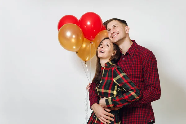 Beautiful caucasian young happy smiling couple in love. Woman and man in plaid checkered clothes with red, yellow balloons, celebrating birthday, on white background isolated. Holiday, party concept. — Stock Photo, Image