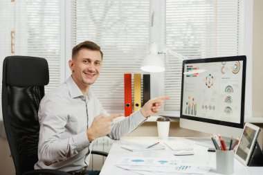 Çalışma masasında oturan gömlek gülümseyen yakışıklı iş adamı