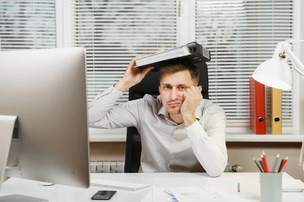 Chocado perplexo e estressado homem de negócios na camisa sentado na mesa, trabalhando no computador com monitor moderno, pastas, lâmpada, documentos em escritório leve no fundo da janela. Gerente ou trabalhador . — Fotografia de Stock