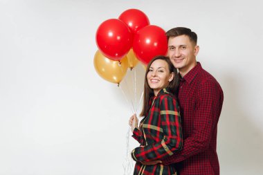 Güzel genç mutlu gülümseyen çift aşık. Kadın ve adam izole beyaz arka plan üzerinde doğum günü kutlama kırmızı, sarı balonları, ekose kareli giysiler içinde. Tatil, parti konsept.