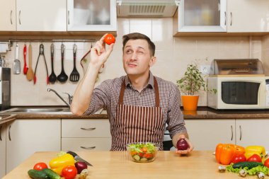 Eğlenceli beyaz genç adam masada oturan önlük, kahverengi gömlekli, 