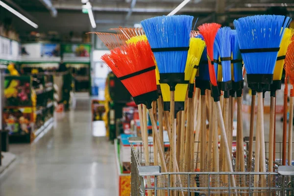 Conjunto de vassouras coloridas para limpeza e varredura na casa em uma grande loja para donas de casa . — Fotografia de Stock