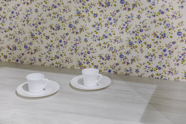 Dos tazas de café blanco dispuestos juntos en la superficie de textura de madera muestran ideas de diseño limpias y simples área de dibujo sobre fondo floral . — Foto de Stock