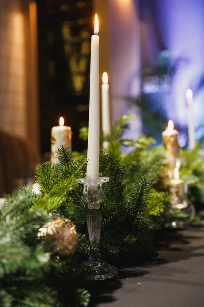Weihnachtlich dekorierter Tisch mit grünen Fichtenzweigen, Kugeln und brennender Kerze im gemütlichen Restaurant. — Stockfoto