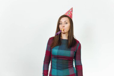 Güzel beyaz eğlence genç mutlu kadın ekose elbise ve doğum günü parti şapkası utangaç bir gülümseme büyüleyici, boru oynatma, kutlama ve beyaz arka plan üzerinde tatil keyfini ile reklam için izole.