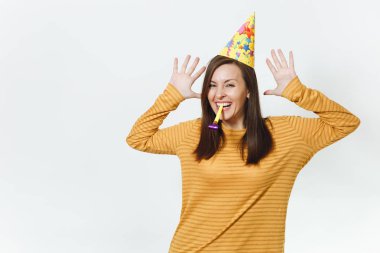 Güzel beyaz eğlenceli boru oynarken, tatil kutluyor, eller için reklam izole beyaz arka plan üzerinde yayılan genç mutlu kadın sarı giysiler ve doğum günü parti şapkası kahverengi uzun saçlı.