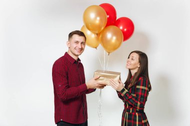 Güzel genç mutlu gülümseyen çift aşık. Kadın ve adam altın hediye kutuları ile tutarak sunmak ve beyaz arka plan üzerinde doğum günü kutlama kırmızı, sarı balonları izole. Tatil, parti konsept.