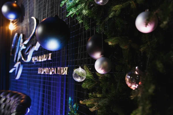 Glänzende Weihnachtskugel, die an grünen Fichtenzweigen mit festlichem Hintergrund in dunkelblauen Farben in einem gemütlich dekorierten Luxusrestaurant hängt. Neujahrsferien-Konzept. — Stockfoto