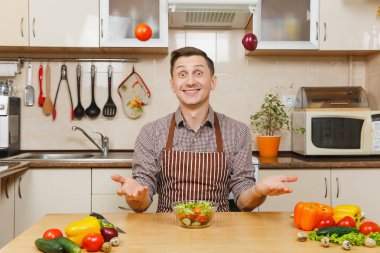 Soğan ve domates, yetişmek sebze salatası kadar ışık mutfak bıçak atma eğlenceli deli beyaz delikanlı masadan, önlük, kahverengi gömlekli. Diyet kavramı. Evde yemek. Yemek hazırlamak.