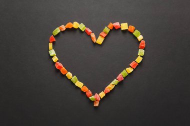 Siyah arka plan üzerine izole kalp şeklinde şekerlenmiş meyve