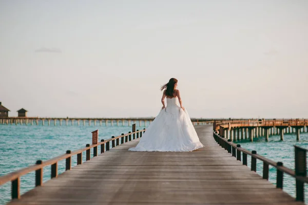 Krásná nevěsta na molu v blízkosti vodních bungalovů — Stock fotografie