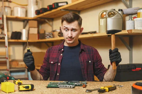 Multímetro para electricista. Hombre joven caucásico en camisa a cuadros, camiseta negra ingeniero electrónico digital reparación, soldadura PC placa base en el taller en la mesa de madera con diferentes herramientas . — Foto de Stock